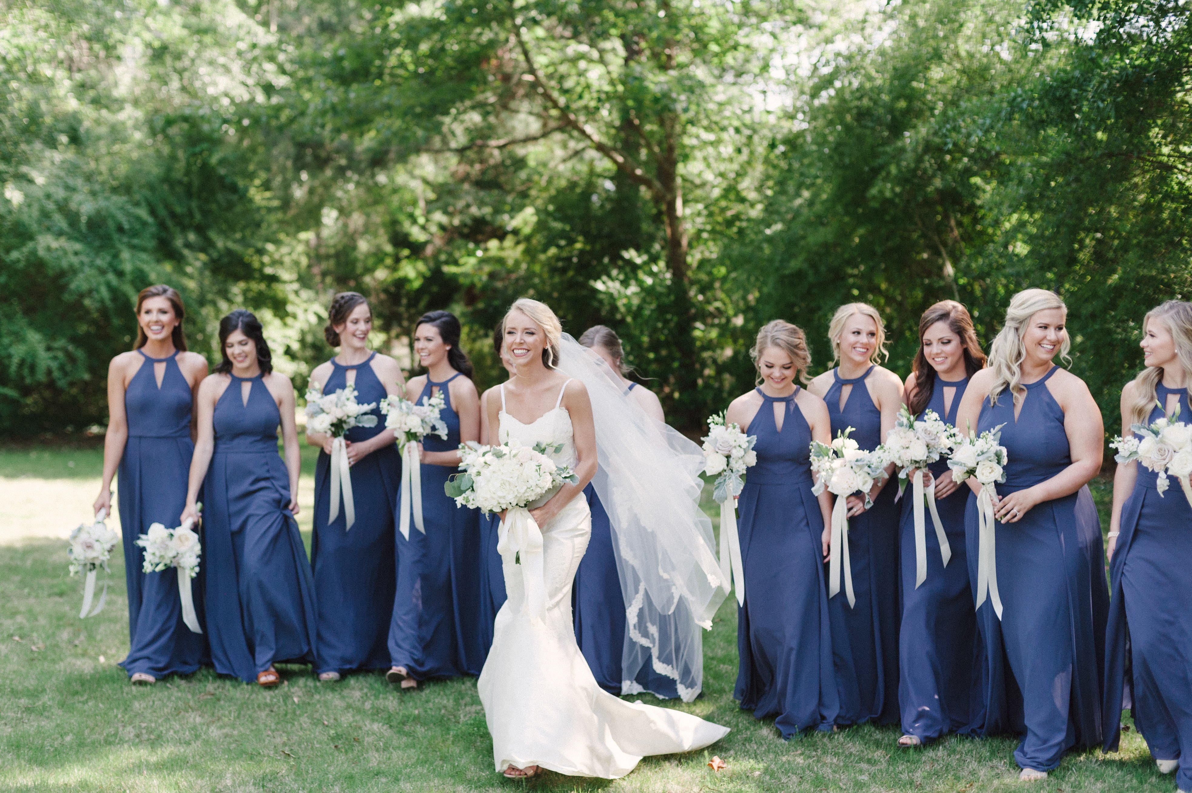 An image of the entire bridal party walking behind bride for her portraits in Selma, AL