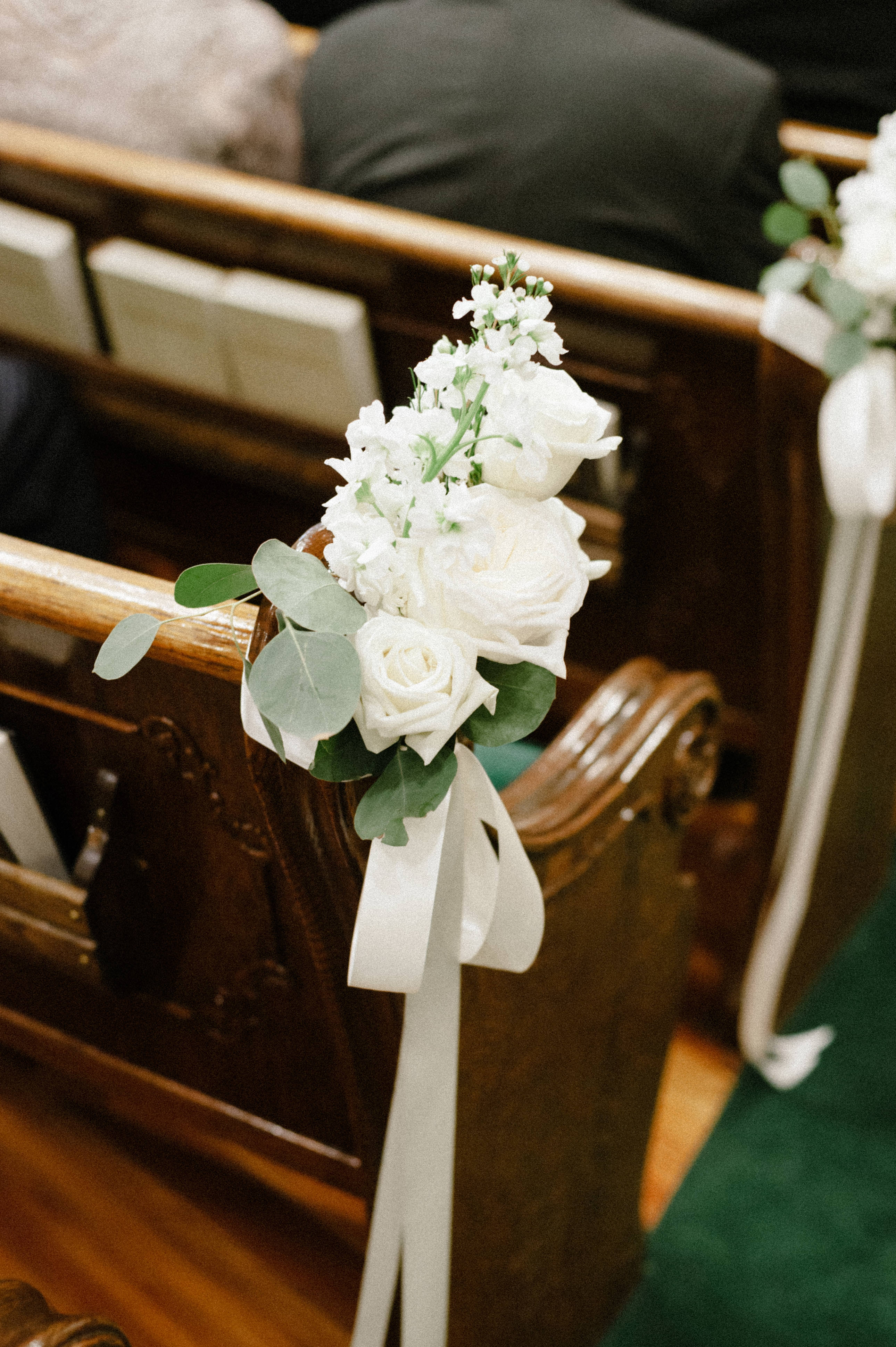 A photo of filmy Portra 400 edit of indoor floral arrangement in tradition church pew at First Baptist Church in Selma, AL