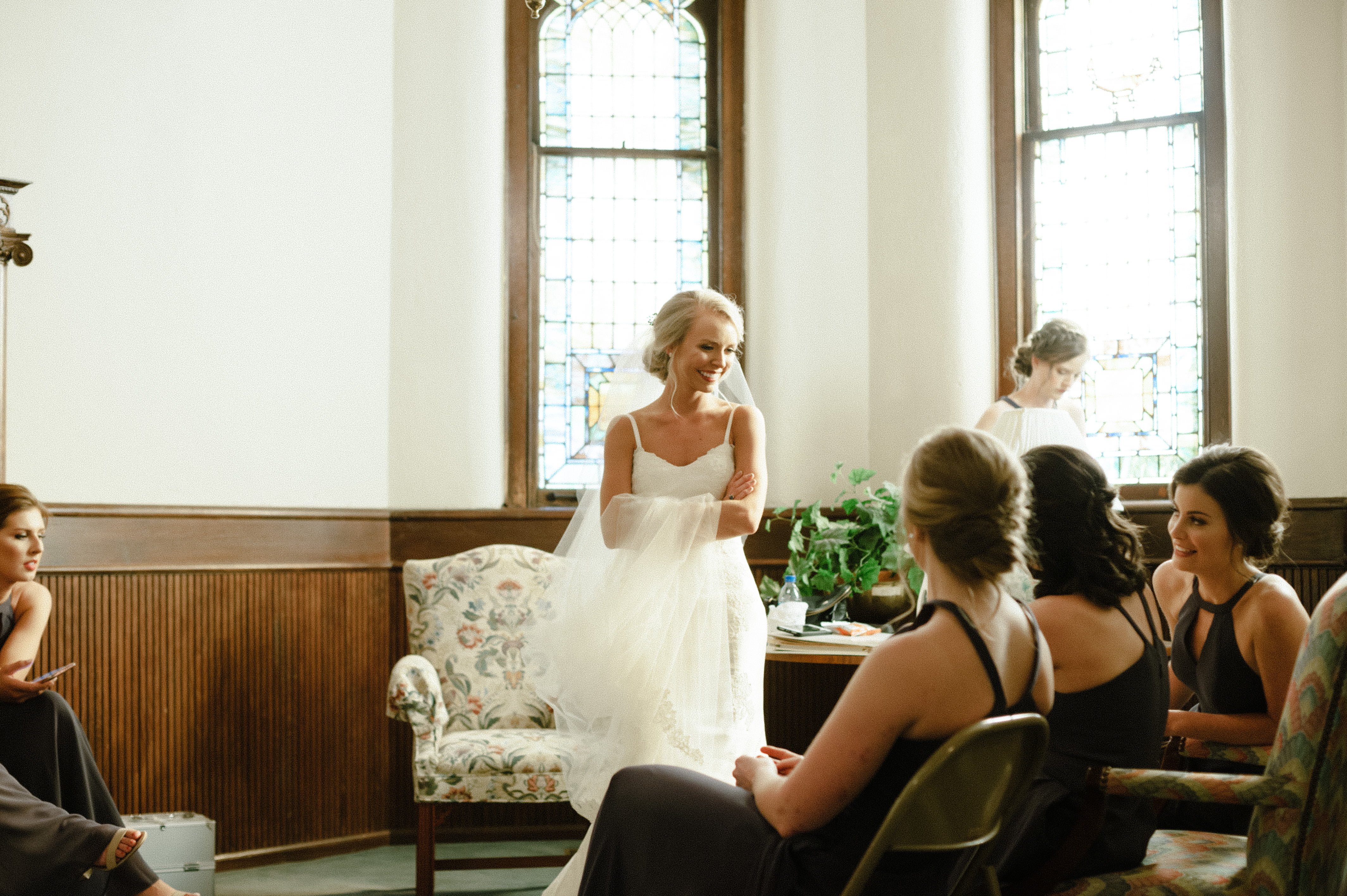 A photo of a joyful bride talking to her bridesmaids minutes before she walks down the aisle for her ceremony in at First Baptist Church in Selma, AL