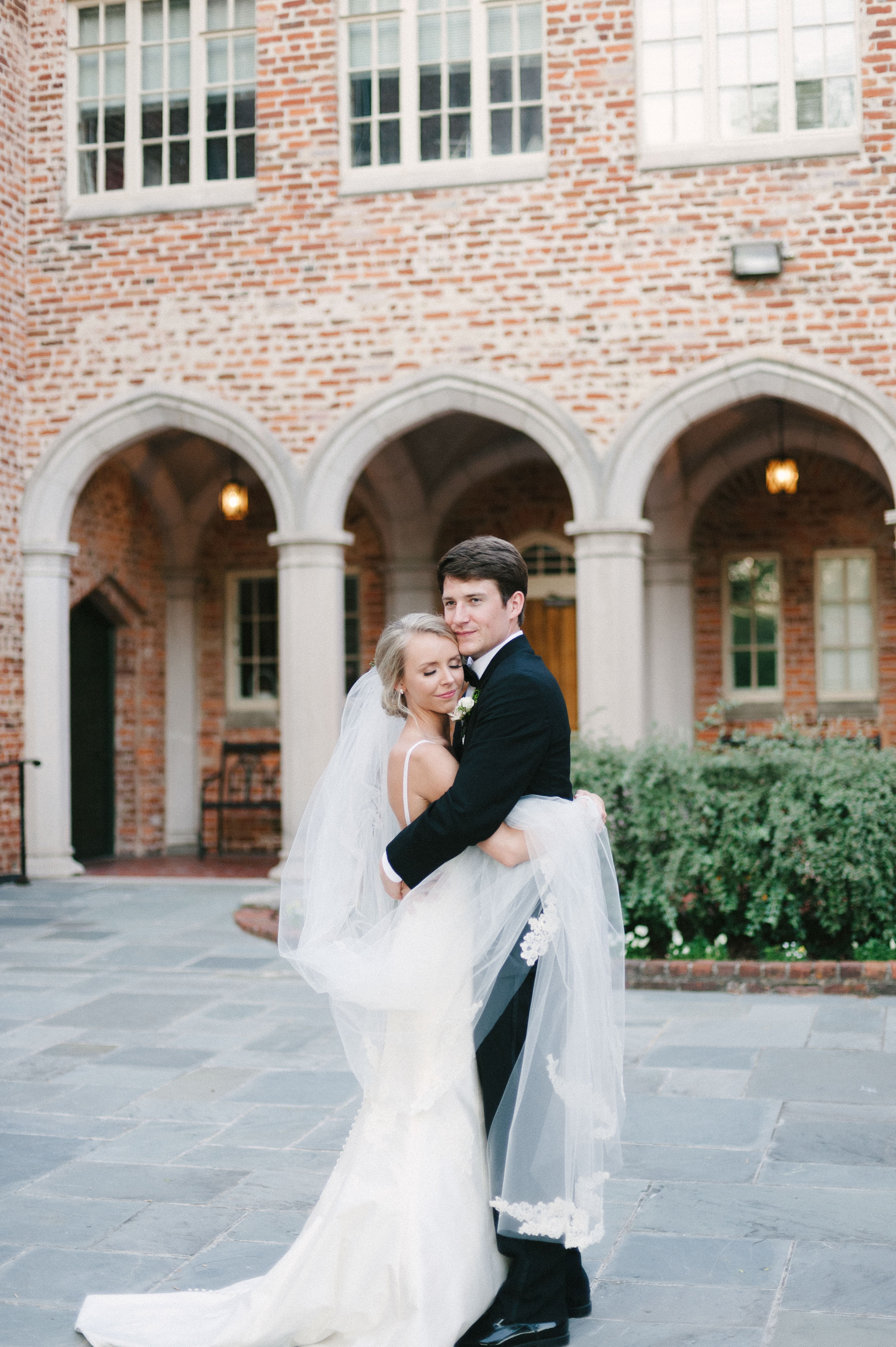 A candid portrait of bride closing her eyes and holding her veil while hugging her brand new groom at First Baptist Church in Selma, AL by Olivia J. Morgan