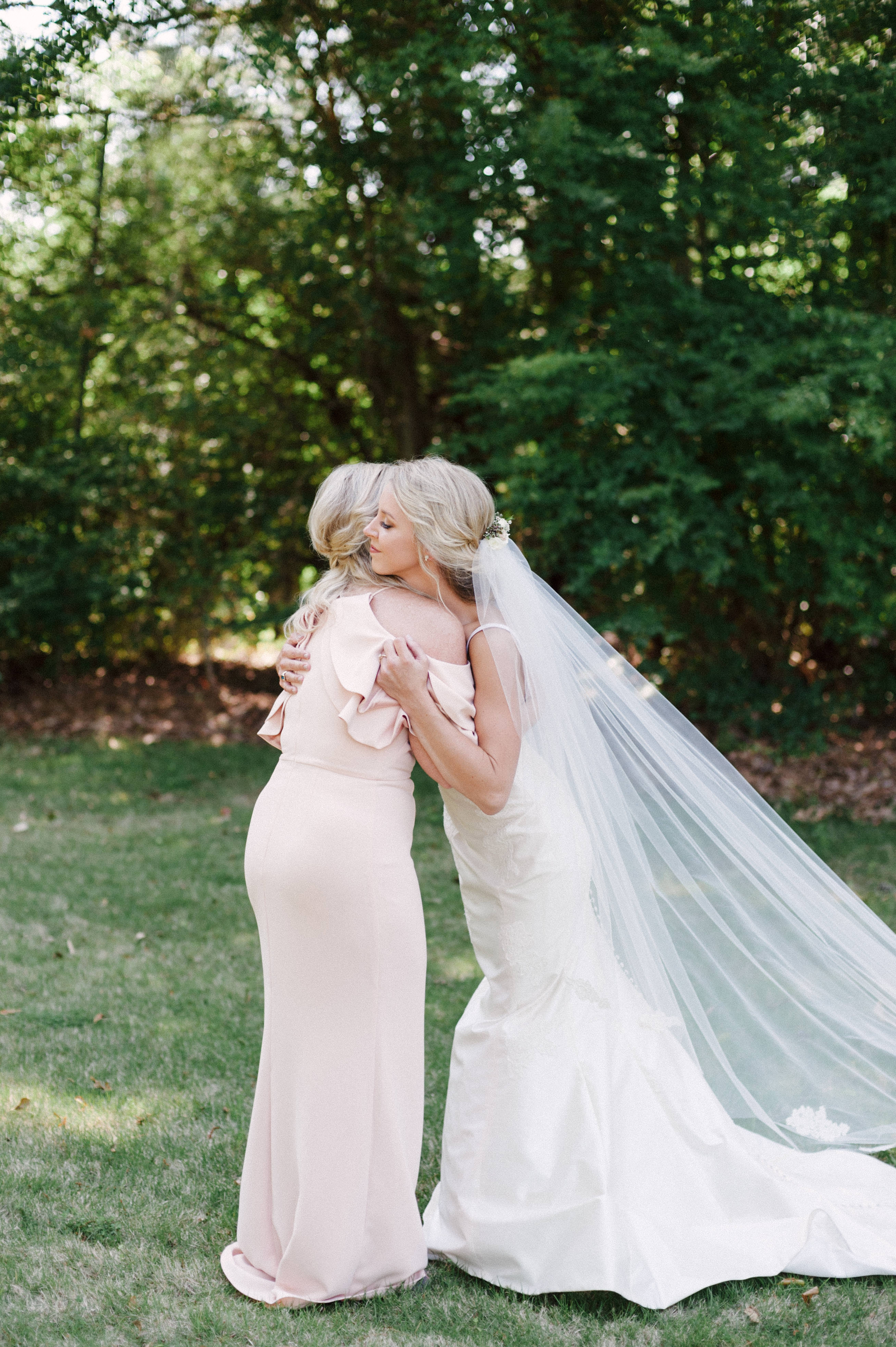 Bride and mother embracing and hugging emotionally near trees at Selma, Alabama wedding