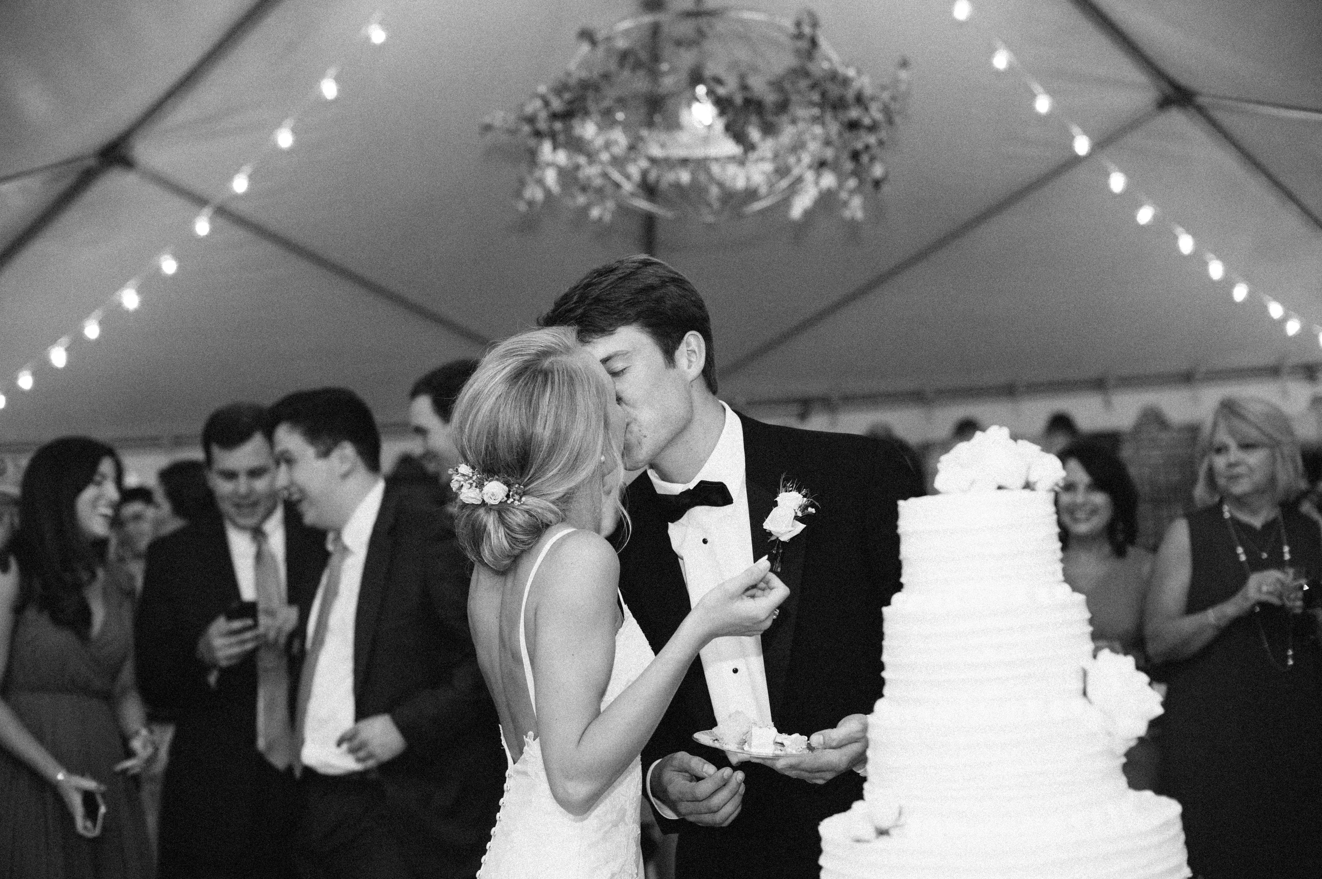More candid bride and groom portrait of them kissing each other after wedding cake cutting in Selma, AL. ilford hp5 edit by Olivia Joy Photography
