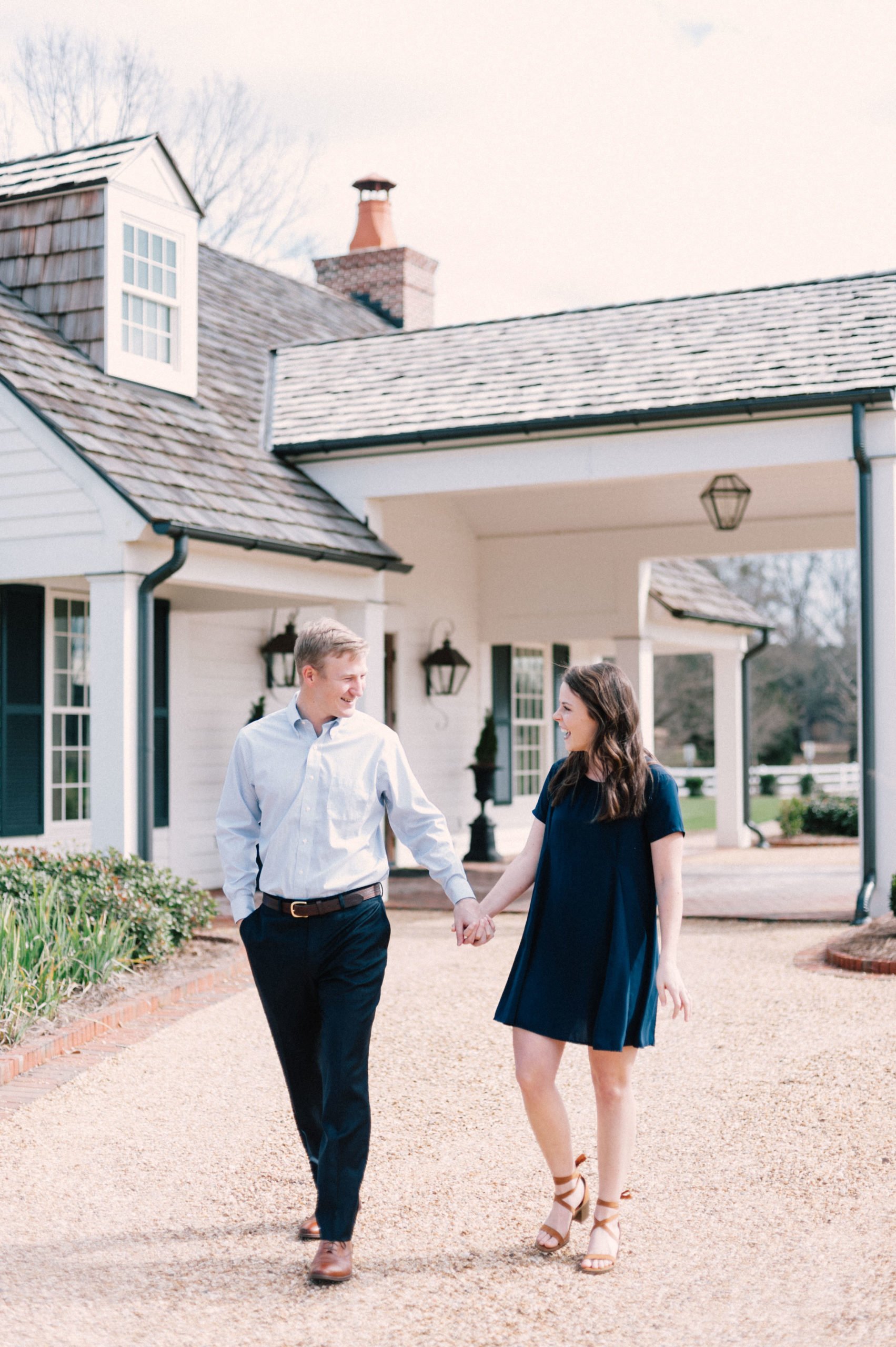 A super happy, newly engaged couple smiling at each other and walking of in front of the clubhouse at Hamilton Place Pursell Farms 