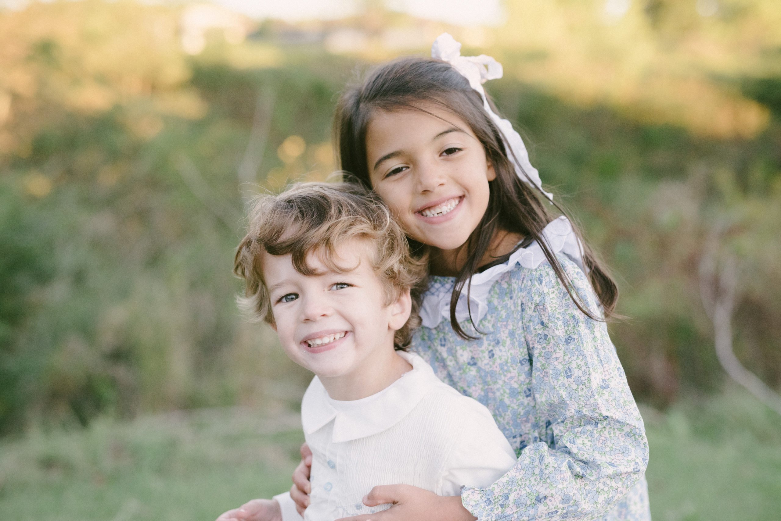 Big sister and little brother smiling at camera for family session