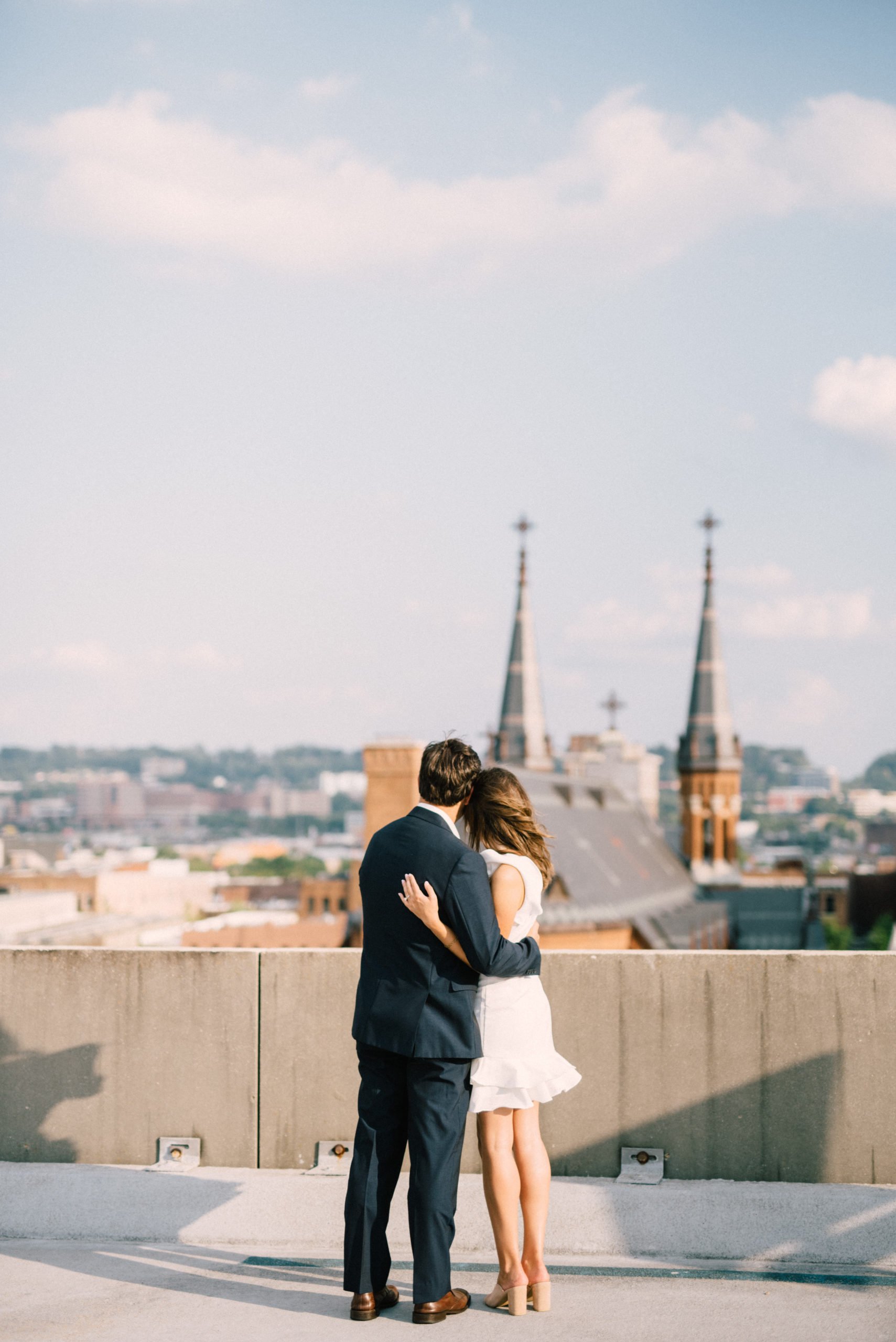 Engaged couple at their engagement session looking from rooftop at St Paul's Cathedral in Birmingham AL