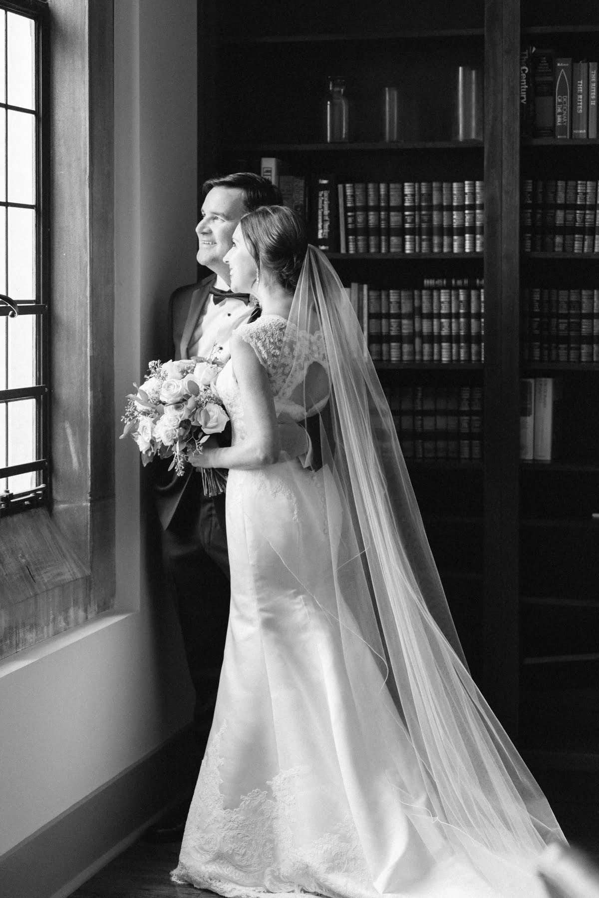 Black and white romantic photo of couple looking outside of window at St Paul's Cathedral library in Birmingham AL