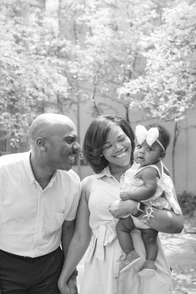 A black and white image of a happy family looking at their daughter while outdoors at Birmingham Art Museum in Alabama