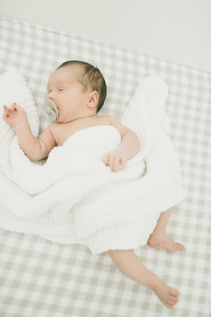 Baby newborn with stylish gingham crib sheets 